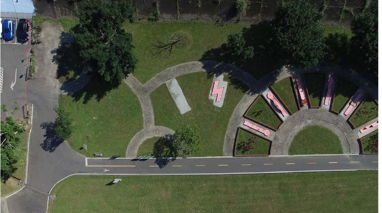 Aerial view of a park with a road and a few parked cars